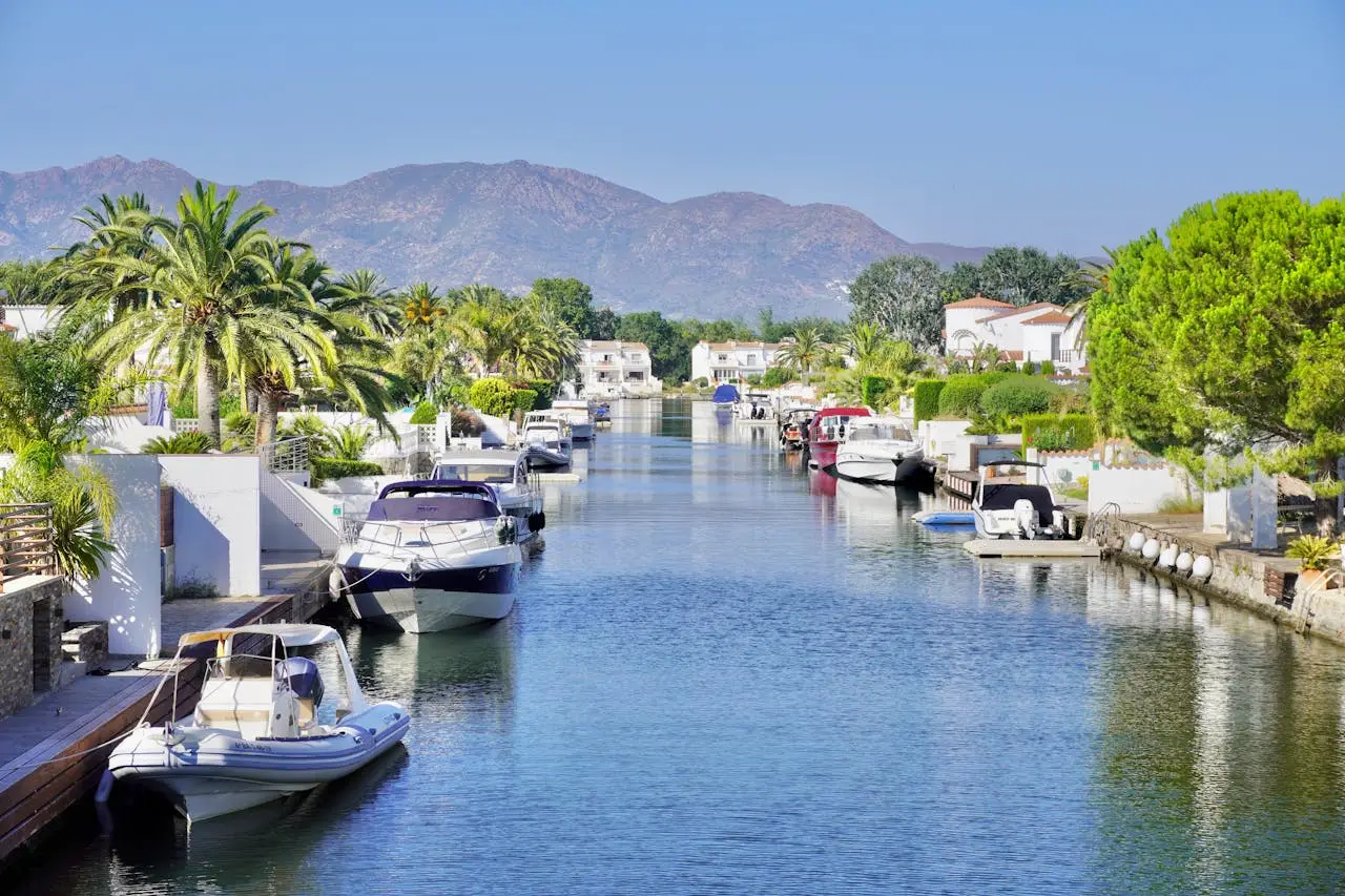 A canal with boats and palm trees in the background